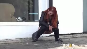Redhead pissing by the shop window
